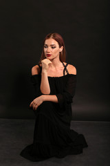 Naklejka premium Studio portrait of pretty woman in black dress on dark background