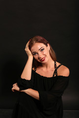 Studio portrait of pretty woman in black dress on dark background