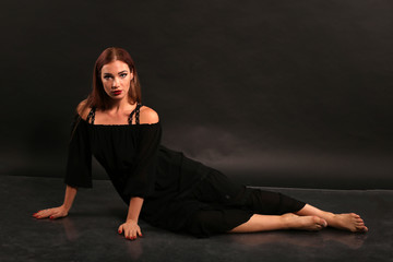 Studio portrait of pretty woman in black dress on dark background