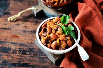 Beef stew with beans, tomatoes and vegetables on a dark wooden background