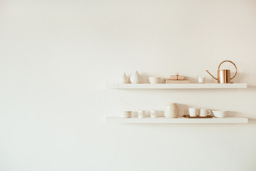 Kitchenware utensils on shelf on white background. Mugs, cups, teapot, tray, decorations. Stylish...