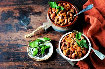 Beef stew with beans, tomatoes and vegetables on a dark wooden background