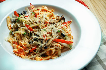 Appetizing, homemade pasta (tagliatelle) with red sauce, cheese and vegetables in white bowl. Traditional italian food. Vegetarian pasta. Close up