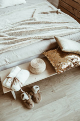 Fototapeta na wymiar Comfortable bed, linen, pillows, slippers, straw basket, dressing gown. Modern classic interior design bedroom concept.