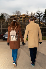 Couple wearing black nitrile gloves and masks walking on the street and holding their hands Selective focus