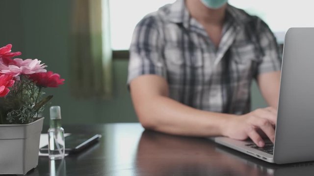 business man working from home using face mask and cleaning hand by alcohol spray for safety from corona virus, covid 19, business concept WFH