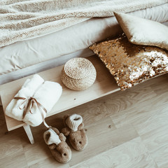 Comfortable bed, linen, pillows, slippers, straw basket, dressing gown. Modern classic interior design bedroom concept.