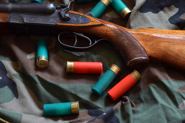 12-gauge rounds and a vintage Soviet shotgun are on camouflage fabric.