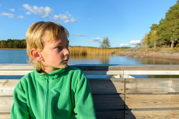 Profile view of young handsome boy thinking at wooden pier
