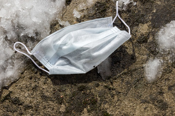 disposable mask lies on the background of the ground,the coronavirus is over, but there are...