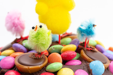 Easter cake on a white background. Close up of fun kids decoration of chocolate frosting covered in colorful chocolate beans and Easter chicks.