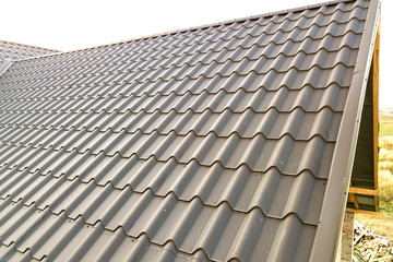 Close up of new house roof structure covered with metal tile sheets.