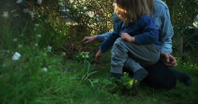 Young mother and preschooler digging in the garden to plant a flower