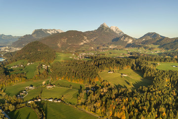 Aerial view of green meadows with villages and forest in austrian Alps mountains.