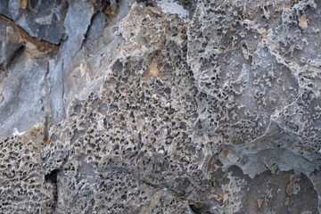 Surface of gray stone rock with a rough porous structure.