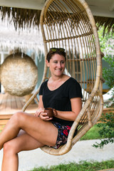 Frau entspannt im Urlaub in einem Hängesessel auf der Veranda