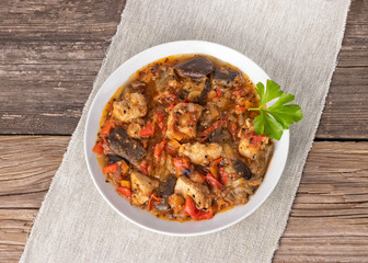Top view of a dish with stew on a napkin on a wooden surface