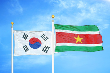 South Korea and Suriname two flags on flagpoles and blue cloudy sky