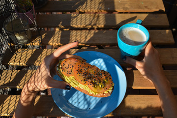 Desayunando en la terraza en un día soleado, tostada integral, aguacate, guacamole,  tomate, ,semillas de sésamo y café