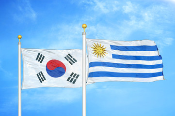 South Korea and Uruguay two flags on flagpoles and blue cloudy sky