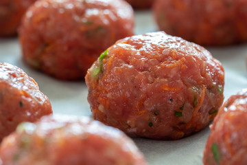 Raw cutlets of ground beef with carrots and herbs before the oven on a baking