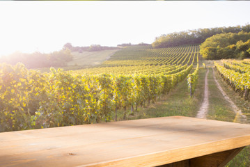 Brown wood table in autumn vineyard landscape with empty copy space on the table for product display mockup. Winery and wine tasting concept.