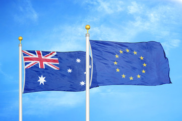 Fototapeta premium Australia and European Union two flags on flagpoles and blue cloudy sky