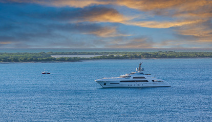 A large, luxury yacht in a calm blue bay