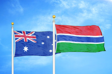 Australia and Gambia two flags on flagpoles and blue cloudy sky