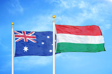 Australia and Hungary two flags on flagpoles and blue cloudy sky