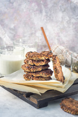Oatmeal raisin on paper and a wooden stand with milk in the background