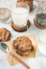 Oatmeal with raisins in a stack on paper on a light background with milk and ingredients on a sunny day