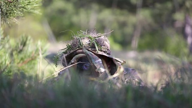 close-up. Camouflage face paint man watching through binoculars. Ghillie suit