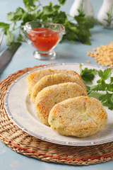 Vegetarian cutlets of peas and semolina in a plate and chili sauce on blue background, Vertical format