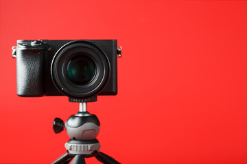 Professional camera on a tripod, on a red background. Record videos and photos for your blog, reportage