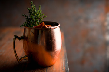 Red oranges cocktail in copper mug (variation of Moscow mule) on the wooden background. Selective focus. Shallow depth of field.
