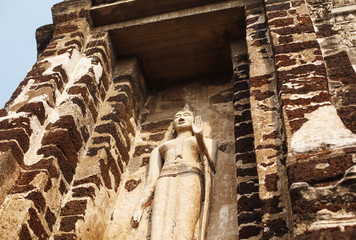 Buddha statue with rised hand from yellow stone. Horizontal shot from below