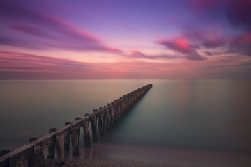 Wooden breakwater in the sea at sunrise in Hindeloopen in Holland.
