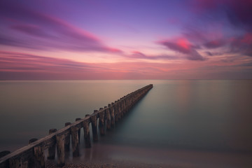 Fototapeta premium Wooden breakwater in the sea at sunrise in Hindeloopen in Holland.