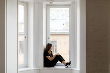 Girl in black clothes near the bay window