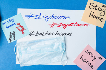 Fototapeta na wymiar hashtag stay home lettering on paper with medical mask and copy space