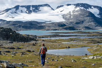 Obraz premium Person walking on a plateau below snowy mountains at Lom, Norway