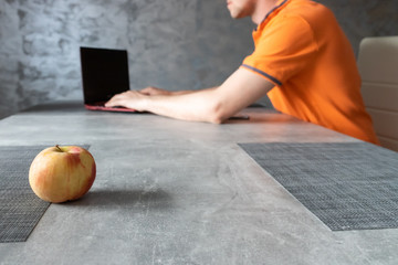 Jabłko na stole, pracujący mężczyzna na laptopie. © andsko