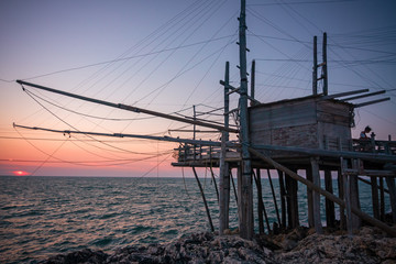 Fototapeta na wymiar Trabucco, ancient wooden structure of the fishermen of the lower Adriatic Sea in the Gargano in Italy, in the sunset light.