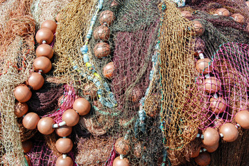 Close up view of fishing nets drying out with floats attached on the side of a harbour
