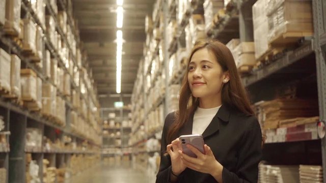 Warehouse clerk Checking products by taking notes via smartphone Before exporting to sell to customers
