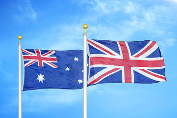 Australia and United Kingdom two flags on flagpoles and blue cloudy sky