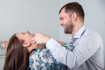 Caucasian man jokingly strangles a woman on a gray background