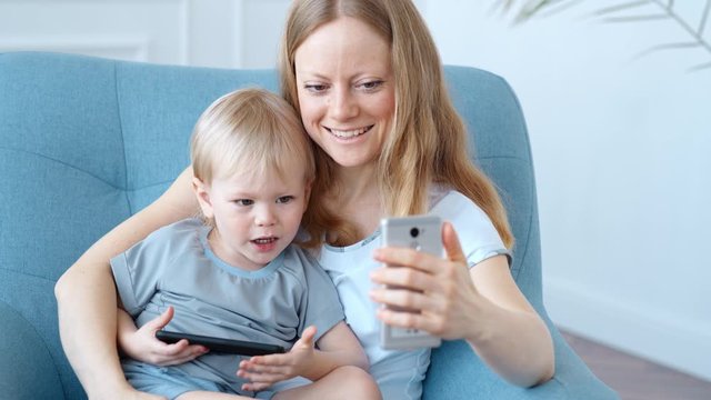 Young mother and son are enthusiastically engaged in online entertainment on a smartphone.