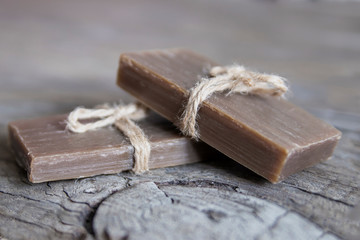 Two pieces of handmade soap tied with jute rope, vintage wooden background.